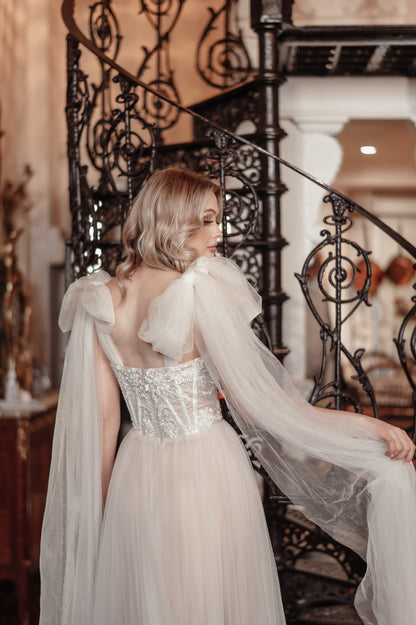 Woman in a elegant white dress with a long train standing in front of a decorative staircase