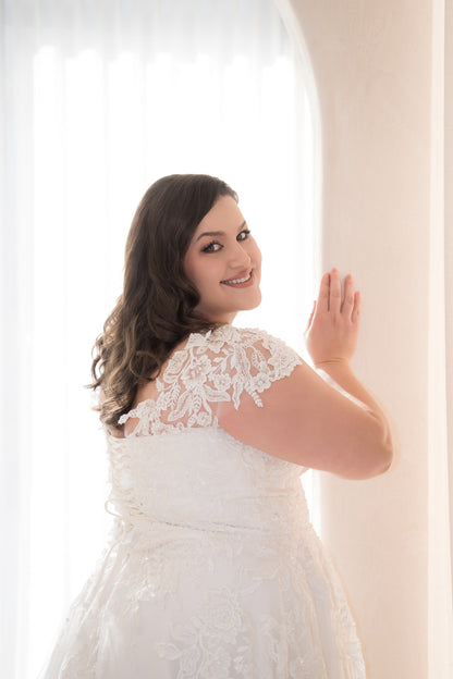 Woman in a white lace dress standing against a light background