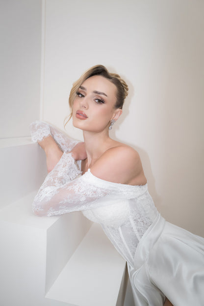 Woman in a white lace dress against a plain background