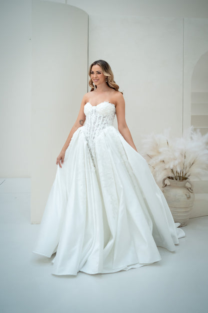 Woman in a white wedding dress standing in a softly lit room with decorative elements.