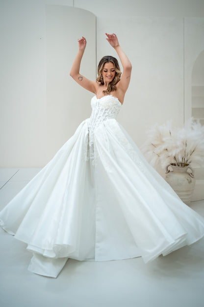 Woman in a white wedding dress standing in a room with white walls and decor.