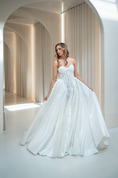 Woman in a white wedding dress standing in a bright, architecturally designed room.