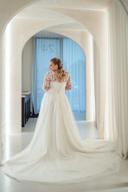 Woman in a white wedding dress standing in a room with arched doorways.