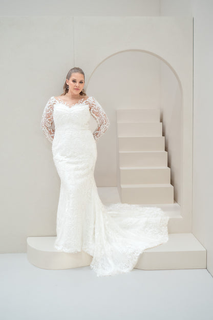 Woman in a white wedding dress standing on a staircase with a neutral background