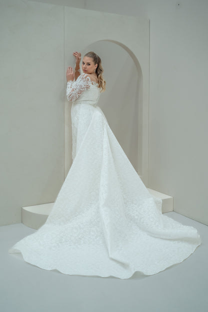 Woman in a white wedding dress standing in a minimalistic room.