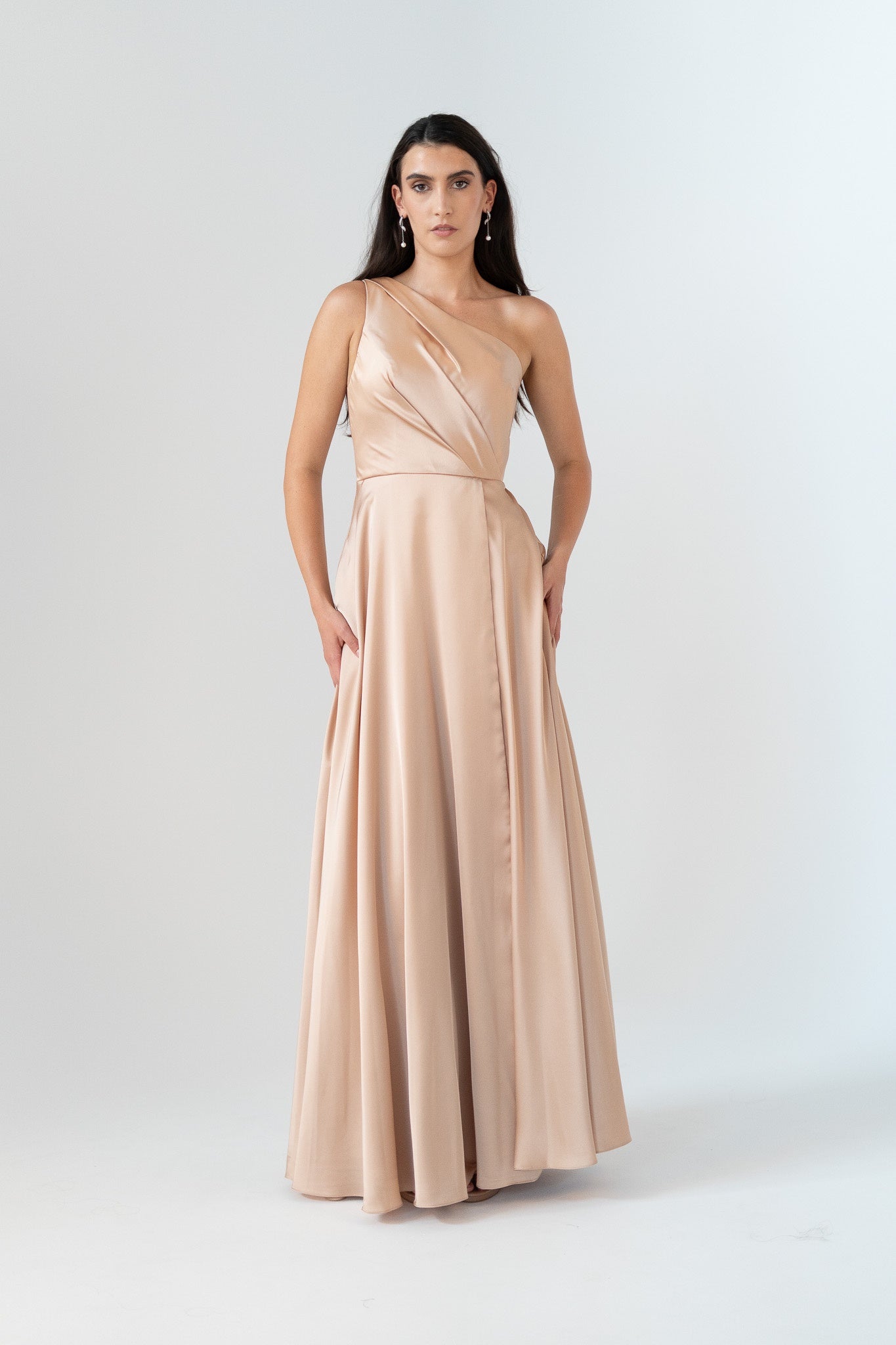 Woman wearing a beige one-shoulder gown on a white background