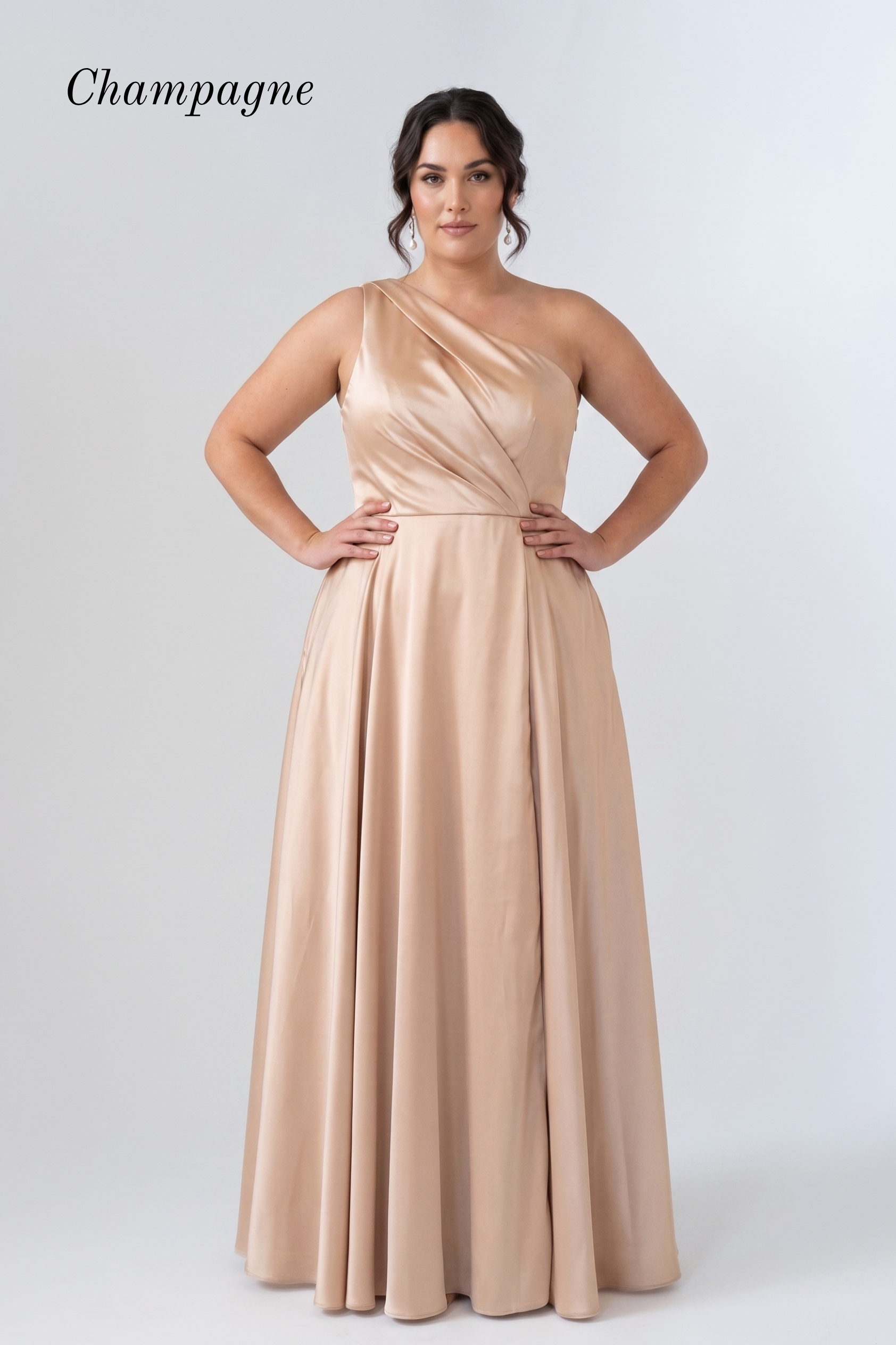 A woman modeling a floor-length champagne one-shoulder gown against a light gray studio background. The word 'Champagne' appears in the upper left corner.