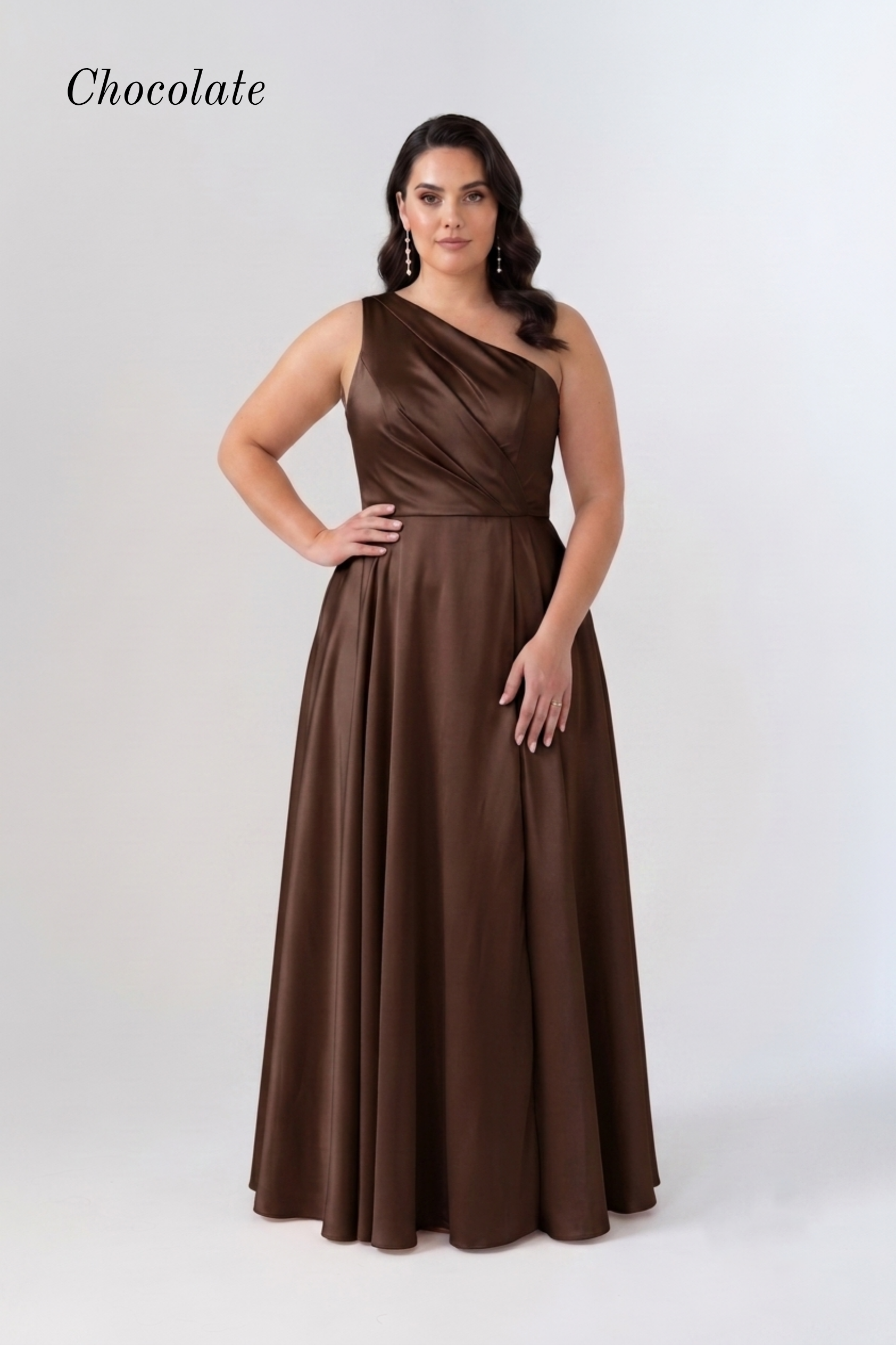 A woman modeling a chocolate brown one-shoulder floor-length gown against a light gray studio background. The word 'Chocolate' appears in the upper left corner.