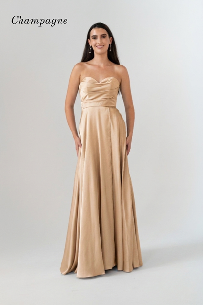 A woman modeling a strapless champagne A-line formal gown against a light gray studio background. The word 'Champagne' is printed in the upper left corner.