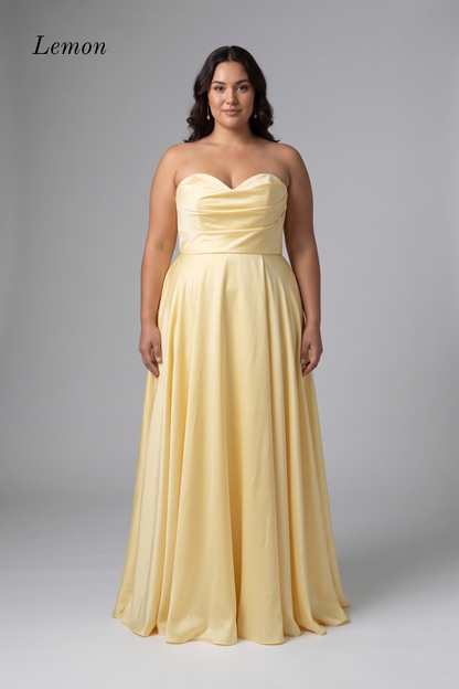 A woman modeling a strapless lemon yellow floor-length gown with a sweetheart neckline, ruched bodice, and flowing skirt against a light gray studio background. The word 'Lemon' appears in the upper left corner.