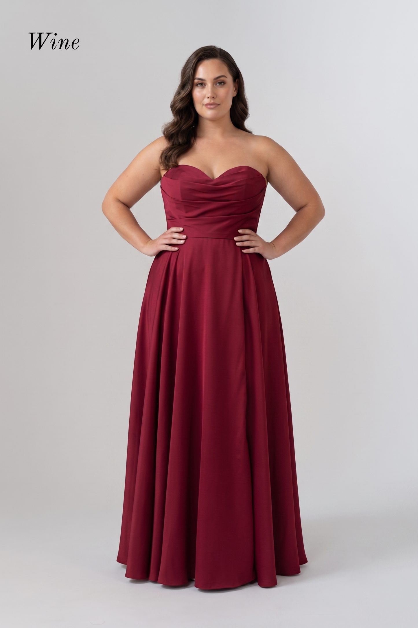 A woman modeling a floor-length strapless gown in a deep wine red color, standing against a light gray studio background. The word 'Wine' appears in the upper left corner.