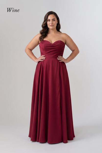 A woman modeling a floor-length strapless gown in a deep wine red color, standing against a light gray studio background. The word 'Wine' appears in the upper left corner.