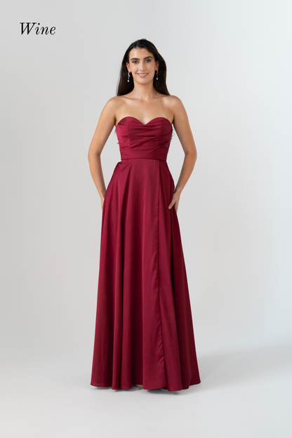 A woman modeling a strapless floor-length gown in a deep wine red color, standing against a light gray studio background. The word 'Wine' appears in the upper left corner.