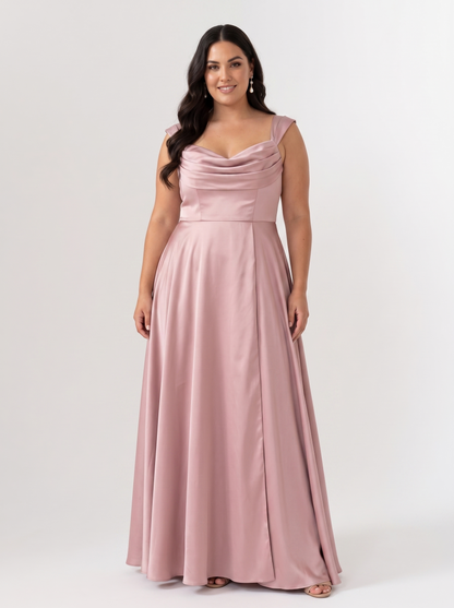 A woman modeling a floor-length dusty pink satin gown with a draped sweetheart neckline and a fitted waist, photographed against a plain light gray studio background.
