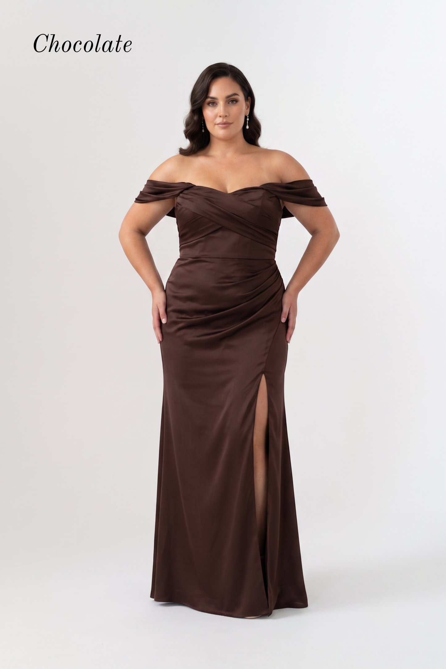 A woman modeling an off-the-shoulder chocolate brown floor-length gown with a ruched bodice and thigh-high slit, shown against a light gray studio background with the word 'Chocolate' in the top left.