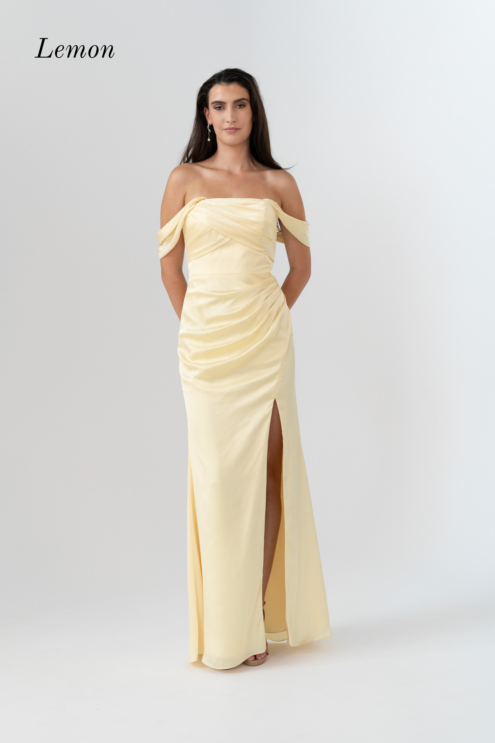 A woman modeling a lemon yellow off-the-shoulder floor-length gown with a ruched bodice and high front slit, photographed against a light gray studio background. The word 'Lemon' appears in the upper left corner.