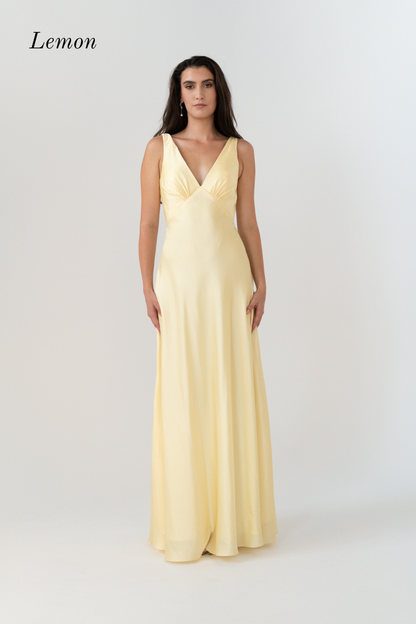A woman modeling a sleeveless, V-neck, floor-length maxi dress in a pale lemon yellow color, set against a plain light gray studio background with the word 'Lemon' in the top left corner.