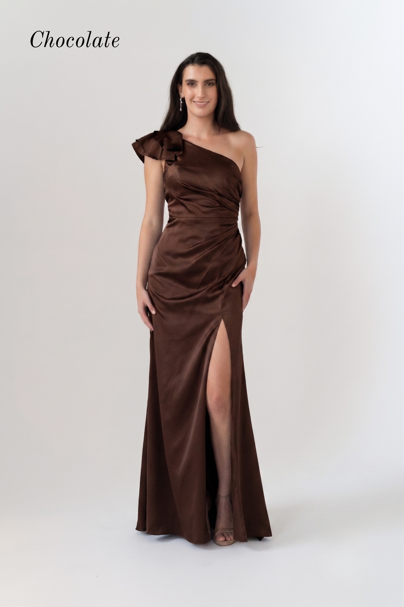 A woman modeling a chocolate brown one-shoulder satin maxi dress with a high thigh slit, set against a plain light gray studio background. The word 'Chocolate' is printed in the upper left corner.