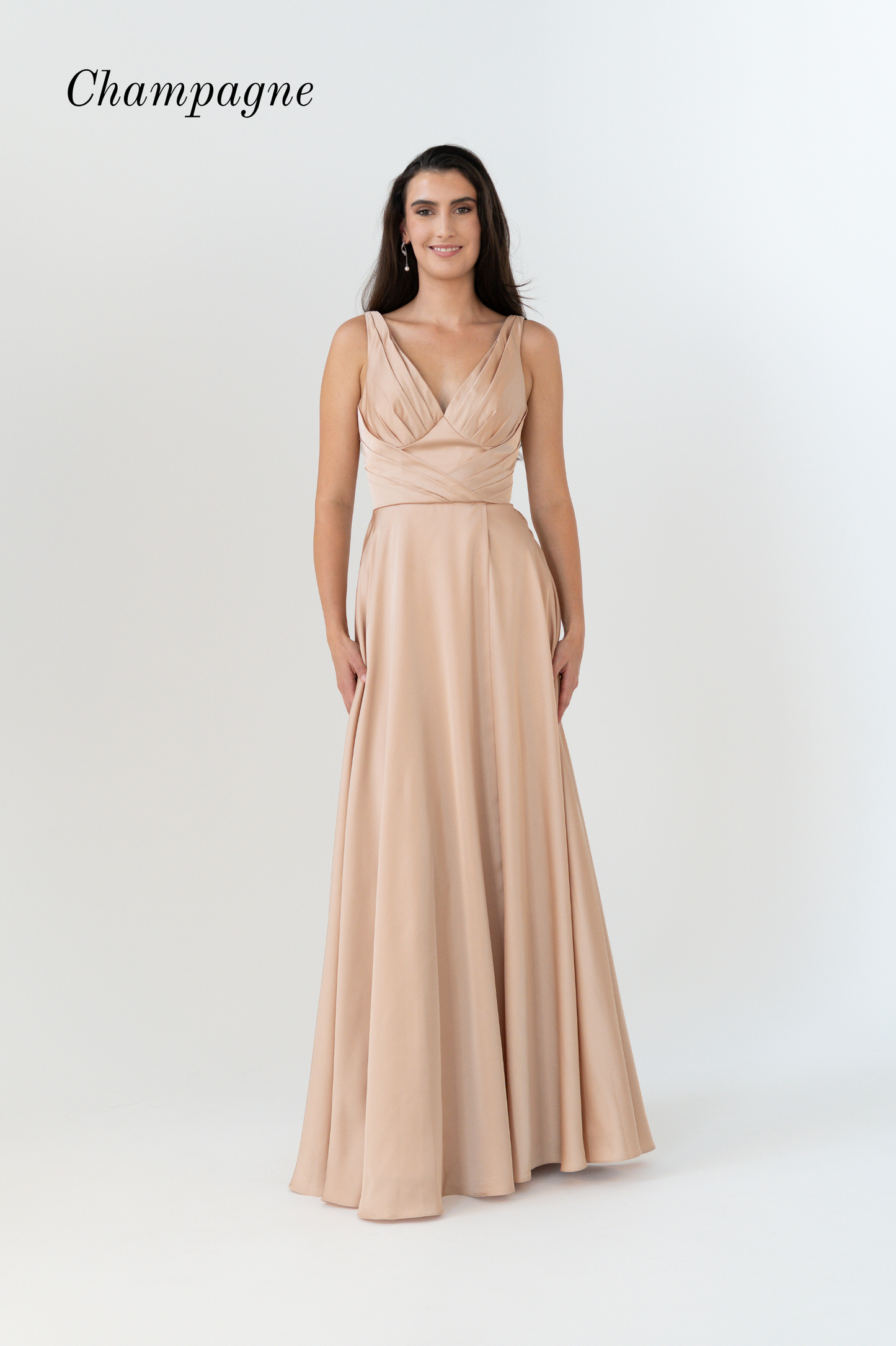 A woman modeling a floor-length champagne gown with a draped, wrap-style bodice and flowing skirt against a light gray studio background. The word 'Champagne' appears in the upper left corner.