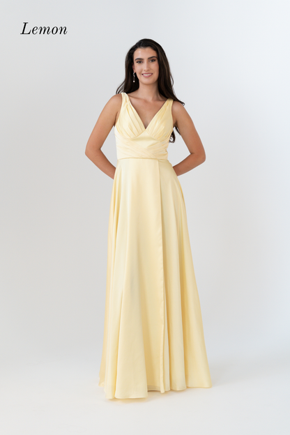 A woman modeling a sleeveless lemon yellow formal gown with a V-neckline and flowing skirt against a light gray studio background. The word 'Lemon' appears in the upper left corner.
