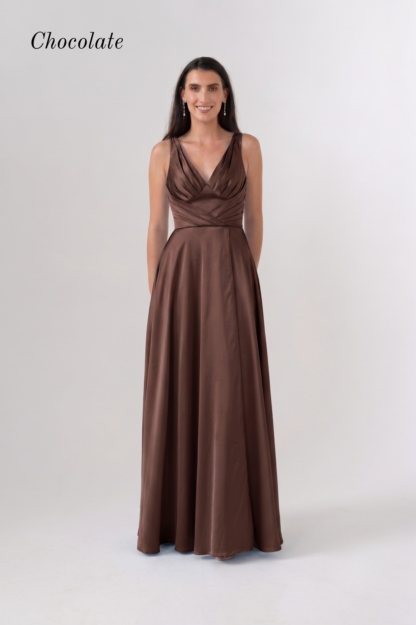 A woman modeling a floor-length chocolate brown gown with a draped, wrap-style bodice and a flowing skirt, photographed against a light gray studio background. The word 'Chocolate' appears in the upper left corner.