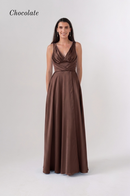 A woman modeling a floor-length chocolate brown gown with a draped, wrap-style bodice and a flowing skirt, photographed against a light gray studio background. The word 'Chocolate' appears in the upper left corner.