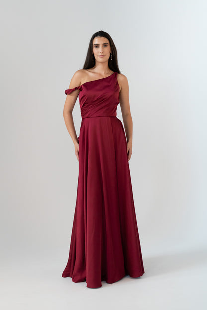 Woman wearing a burgundy one-shoulder gown on a white background