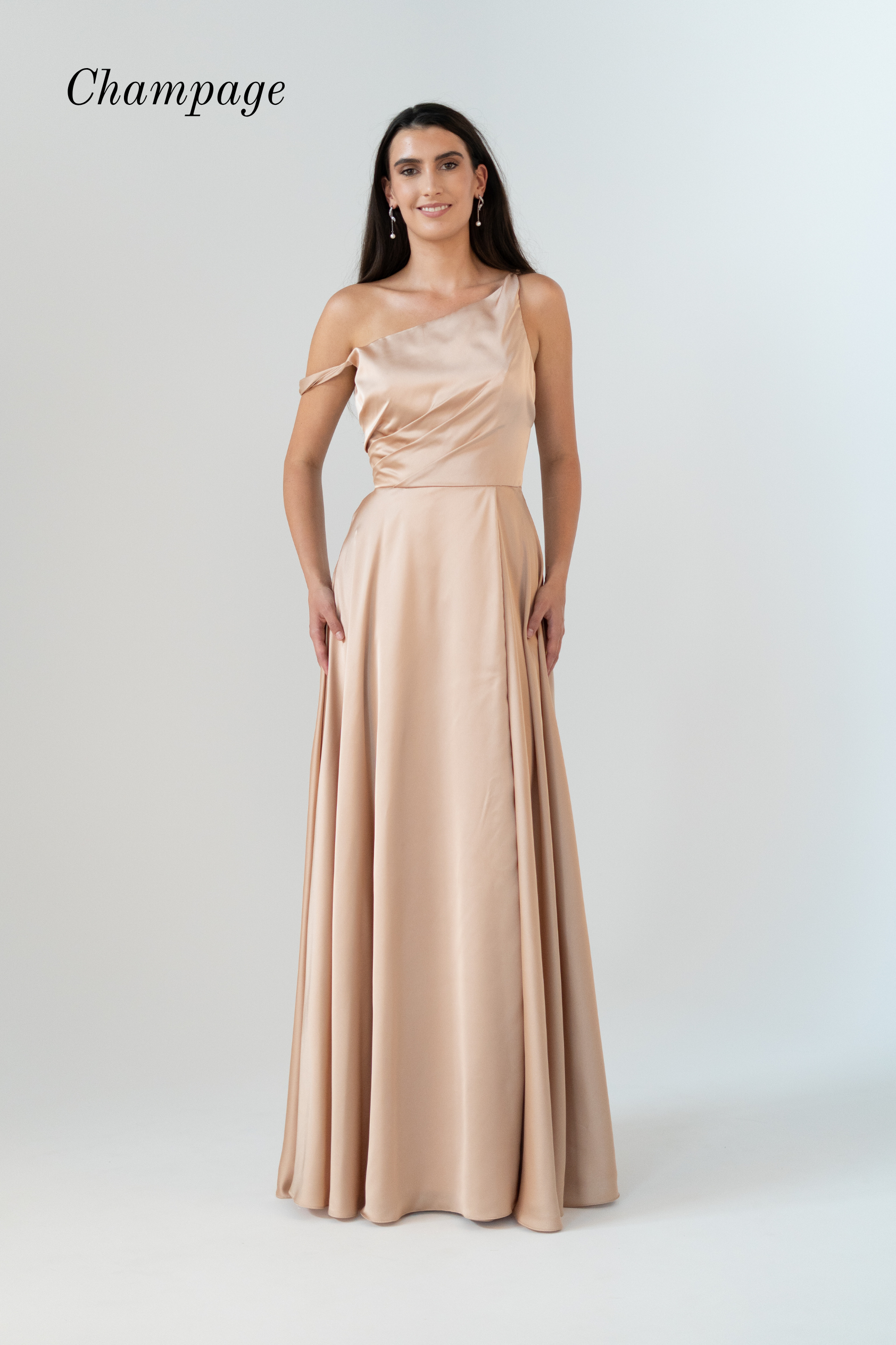 A woman modeling a floor-length champagne satin gown with an asymmetrical draped neckline and a flowing skirt, shown against a light gray studio background with the word 'Champagne' in the upper left.