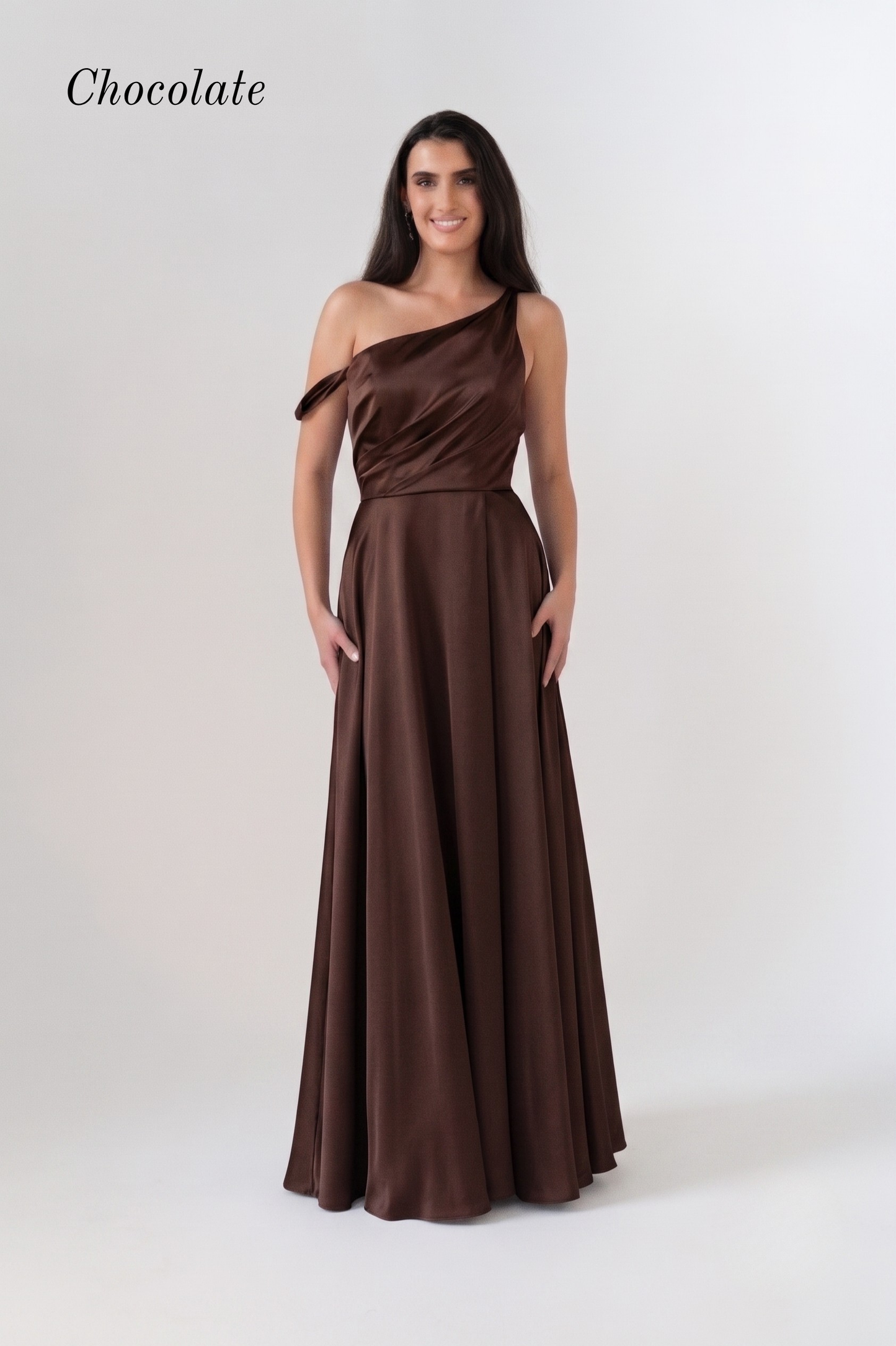 A woman modeling a chocolate brown one-shoulder floor-length gown against a plain light gray studio background. The word 'Chocolate' appears in the upper left corner.