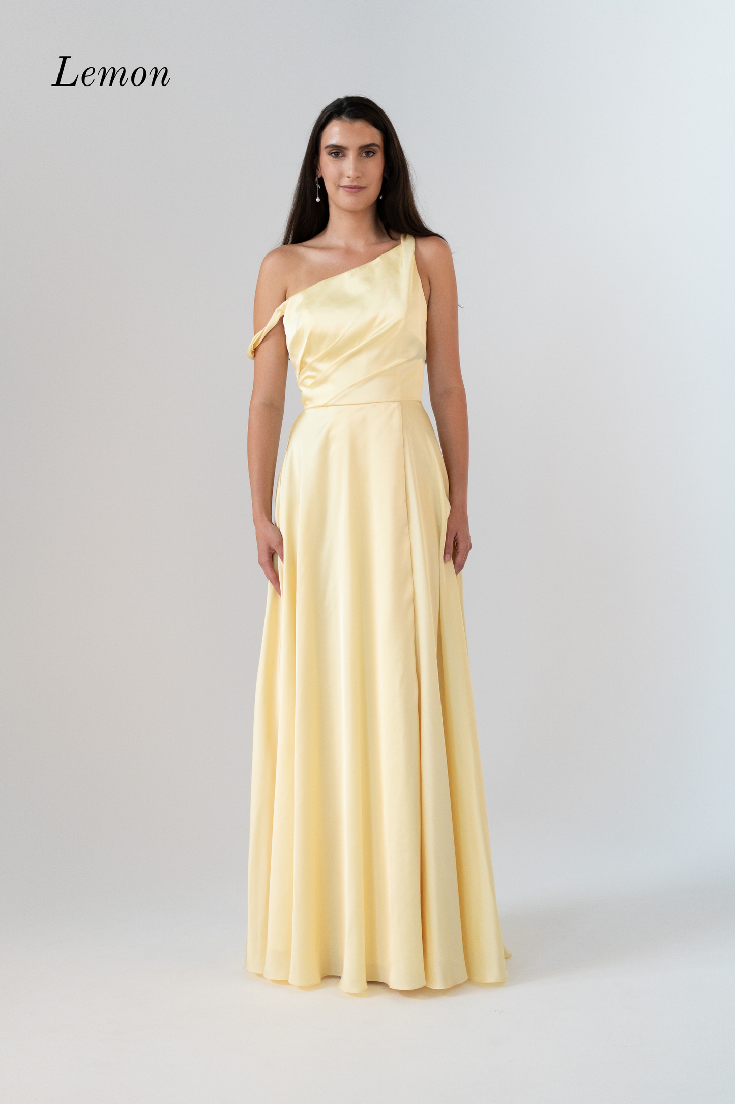 Woman wearing a light yellow one-shoulder gown on a white background