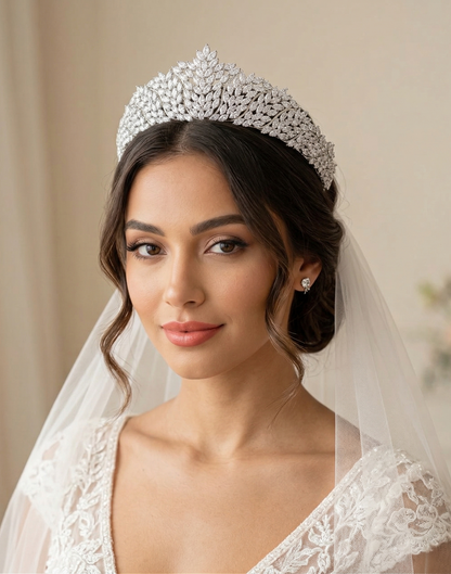 Woman wearing a sparkling tiara and veil against a neutral background