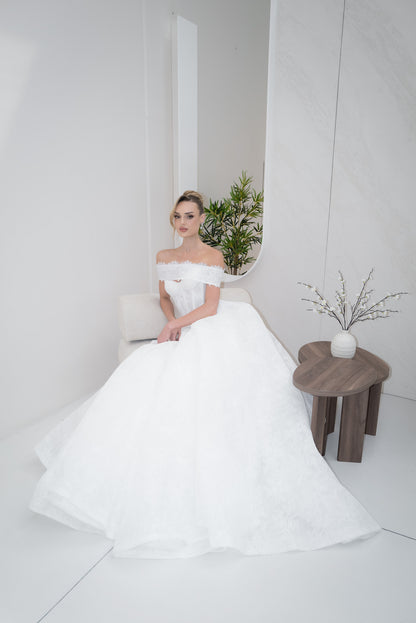 Woman in a white wedding dress sitting on a chair in a minimalistic room.
