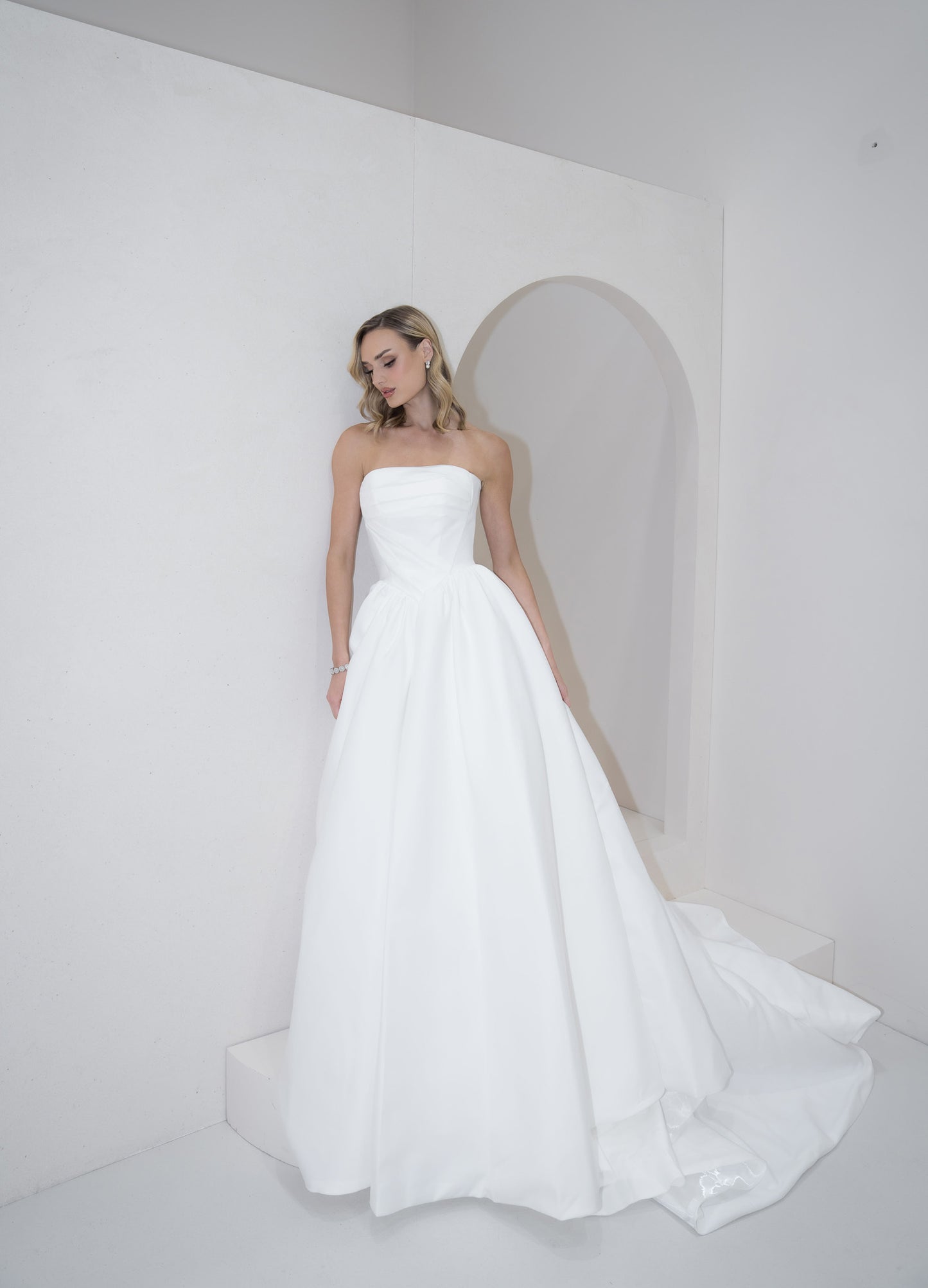 Woman wearing a strapless white wedding dress in a minimalistic setting