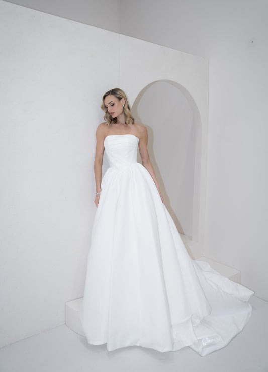 Woman wearing a strapless white wedding dress in a minimalistic setting