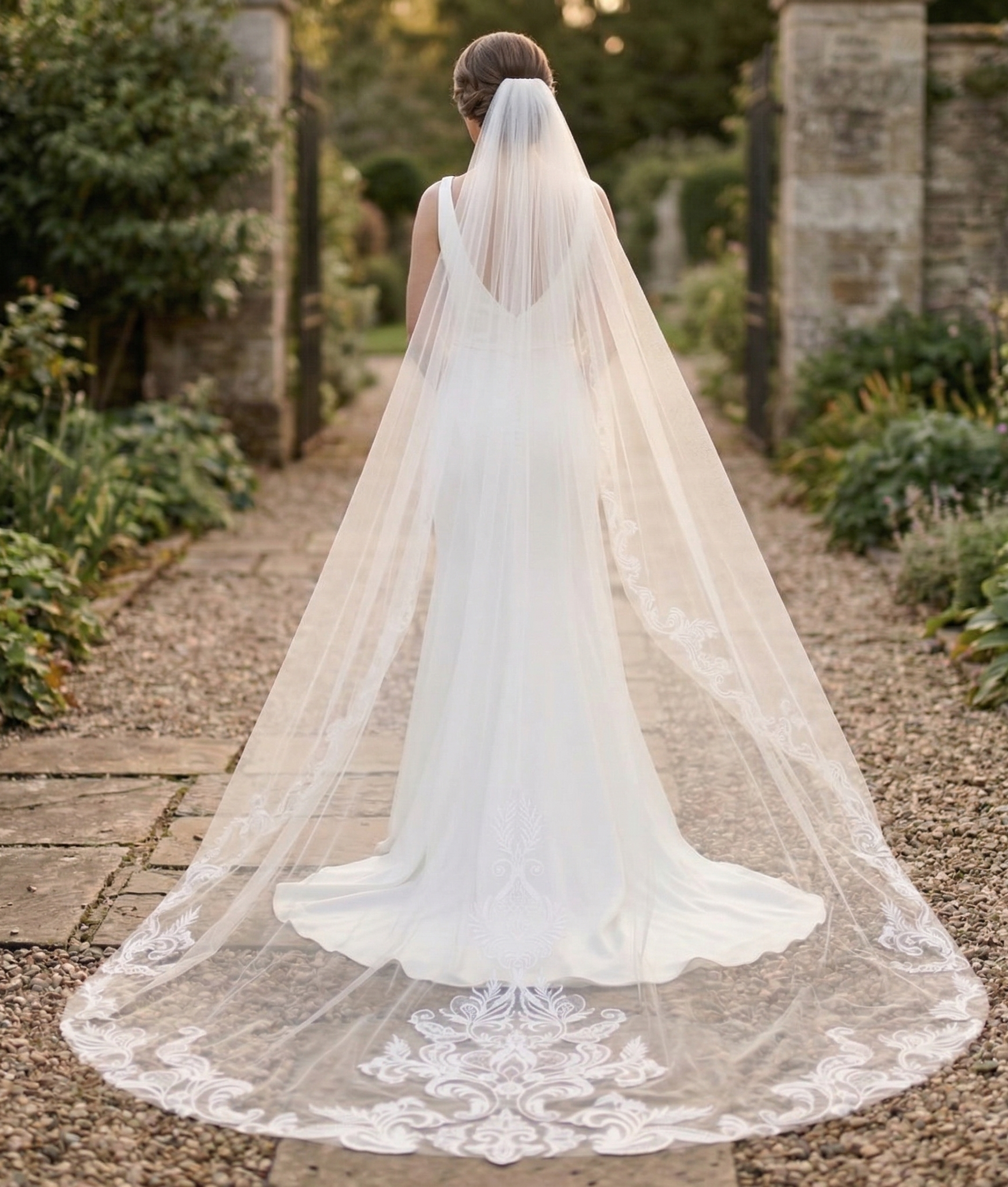 Bride with a long veil walking outdoors in a garden setting