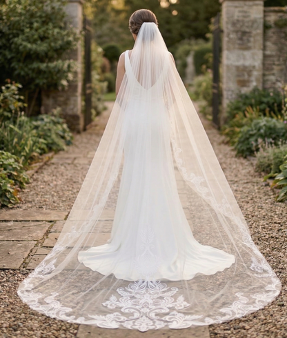 Bride with a long veil walking outdoors in a garden setting