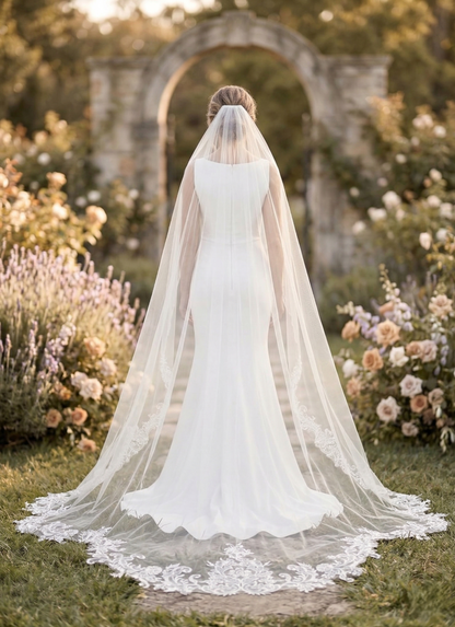 Bride in a white wedding dress with a long veil standing in a garden.
