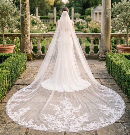 Bride with a long veil standing in an elegant garden setting
