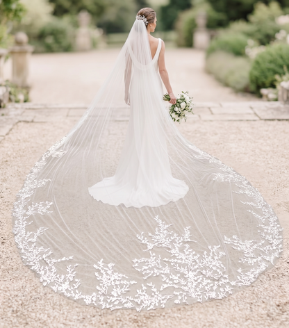 Bride in a white wedding dress with a long veil in an outdoor setting
