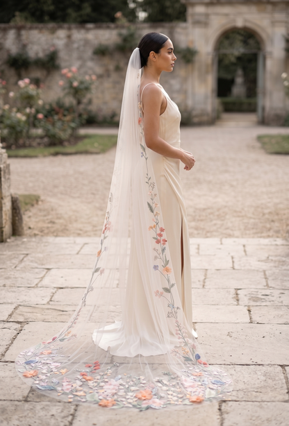 Woman in a floral wedding dress with a long veil in an outdoor setting