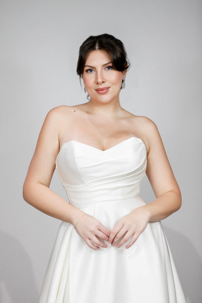 Woman wearing a white strapless dress against a gray background