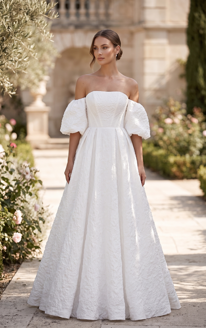 Woman wearing a white off-shoulder dress with puffed sleeves in an outdoor setting.