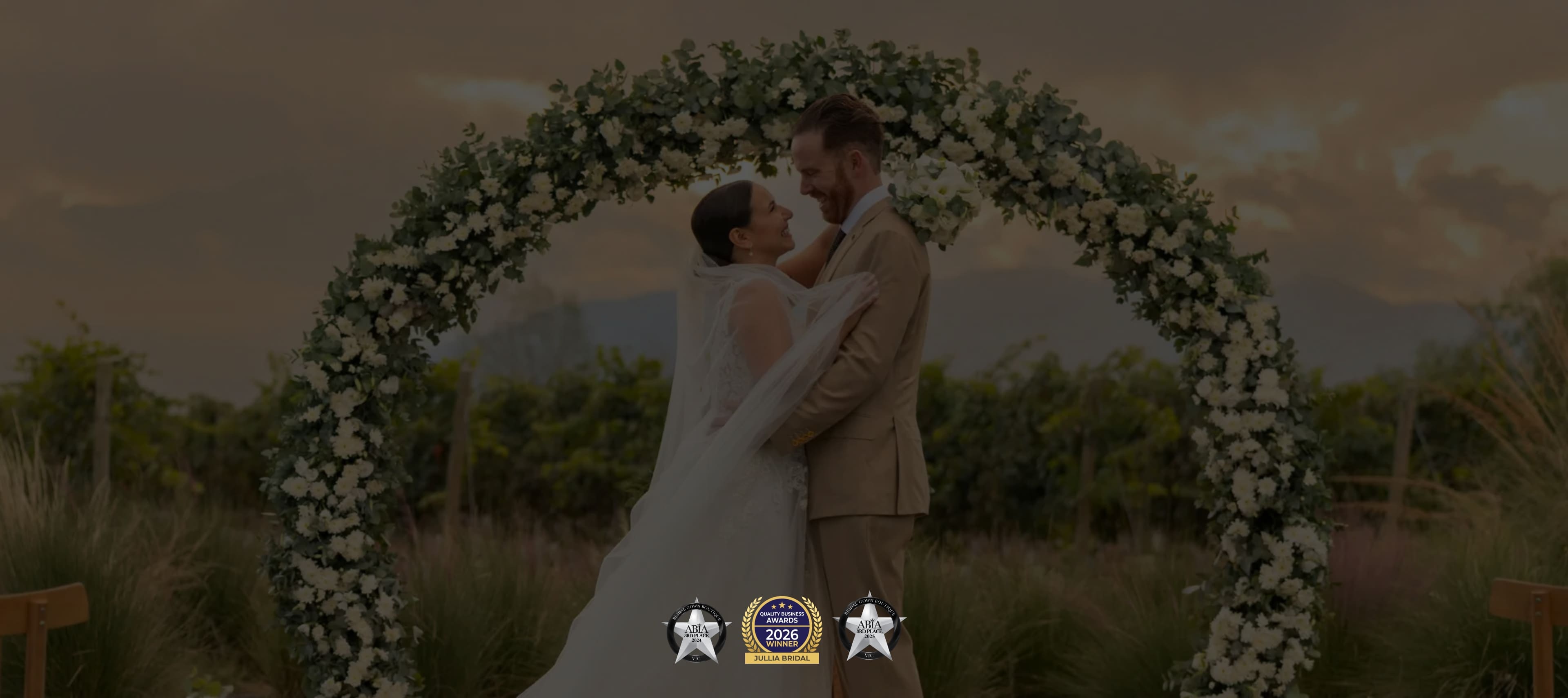 Wedding couple under a floral arch with a scenic background