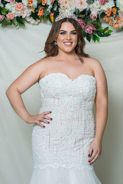 Woman wearing a strapless white wedding dress with floral decorations in the background