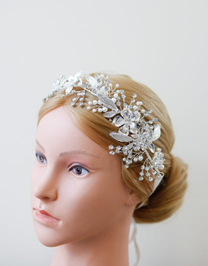 Mannequin head with a decorative silver hairpiece on a plain background