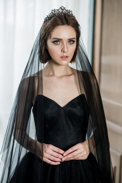 Woman wearing a black dress with a long black veil and tiara indoors