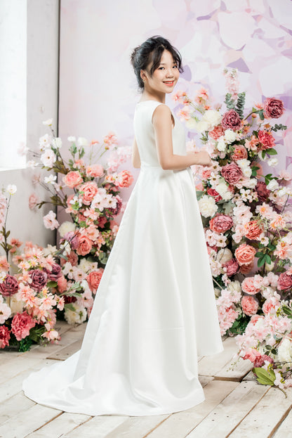Woman in a white dress standing in front of a floral arrangement