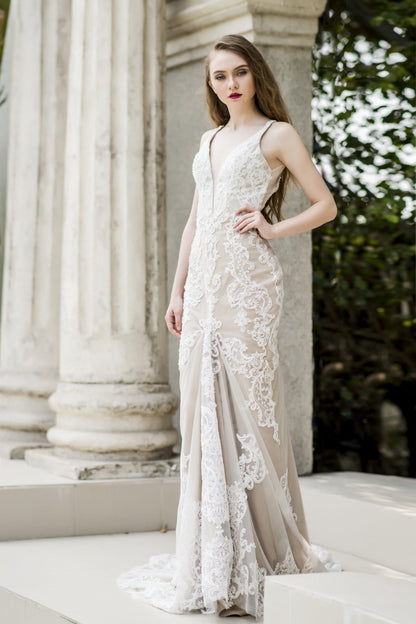 Woman in a white lace dress standing outdoors with classical columns in the background