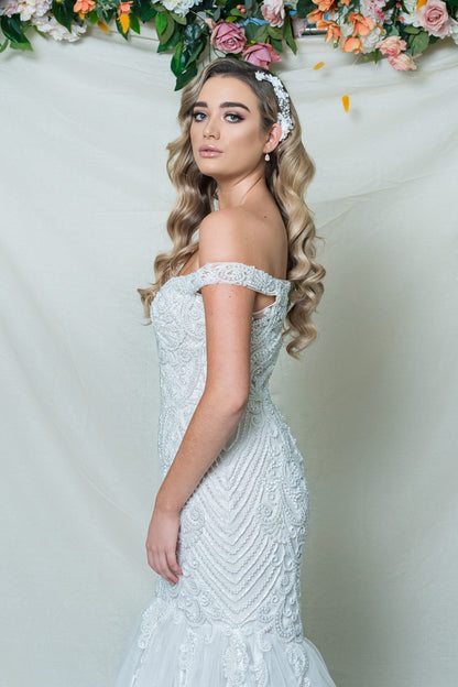 Woman in a white lace wedding dress with floral decorations in the background