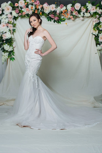Woman in a white wedding dress standing in front of a floral arch